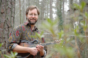 Picture of Charles Pettee in woodland setting holding a mandolin