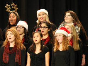 choristers—one with santa hat, one with reindeer antlers