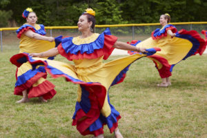 Photo of latina women in brightly colored dresses dancing