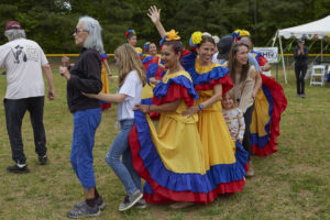 Members of Takiri Folclor Latino, in brightly colored dresses lead an audience participation dance line