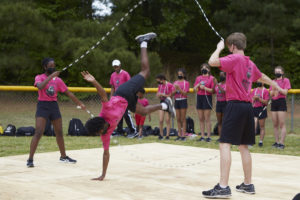 Photo of Bouncing Bulldogs team, with two people holding 2 jump ropes while a third does a hand stand in the middle