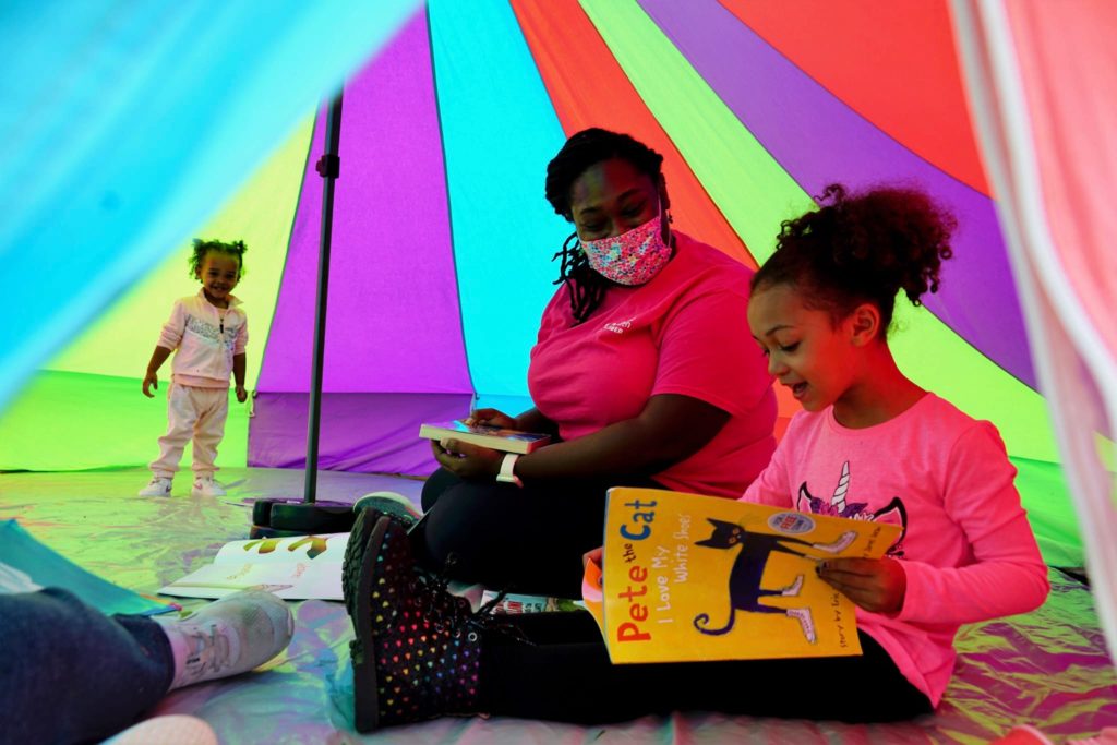 Woman and child read a book inside a colorful tent