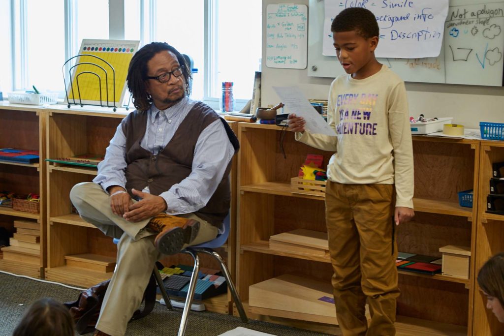 Photo of student reading his poem with Phillip Shabazz