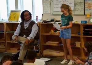 Photo of student reading poem to class with Phillip Shabazz