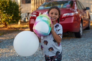 Photo young girl holding a large white balloon and a stuffed unicorn