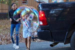 Photo of small girl popping enormous bubble