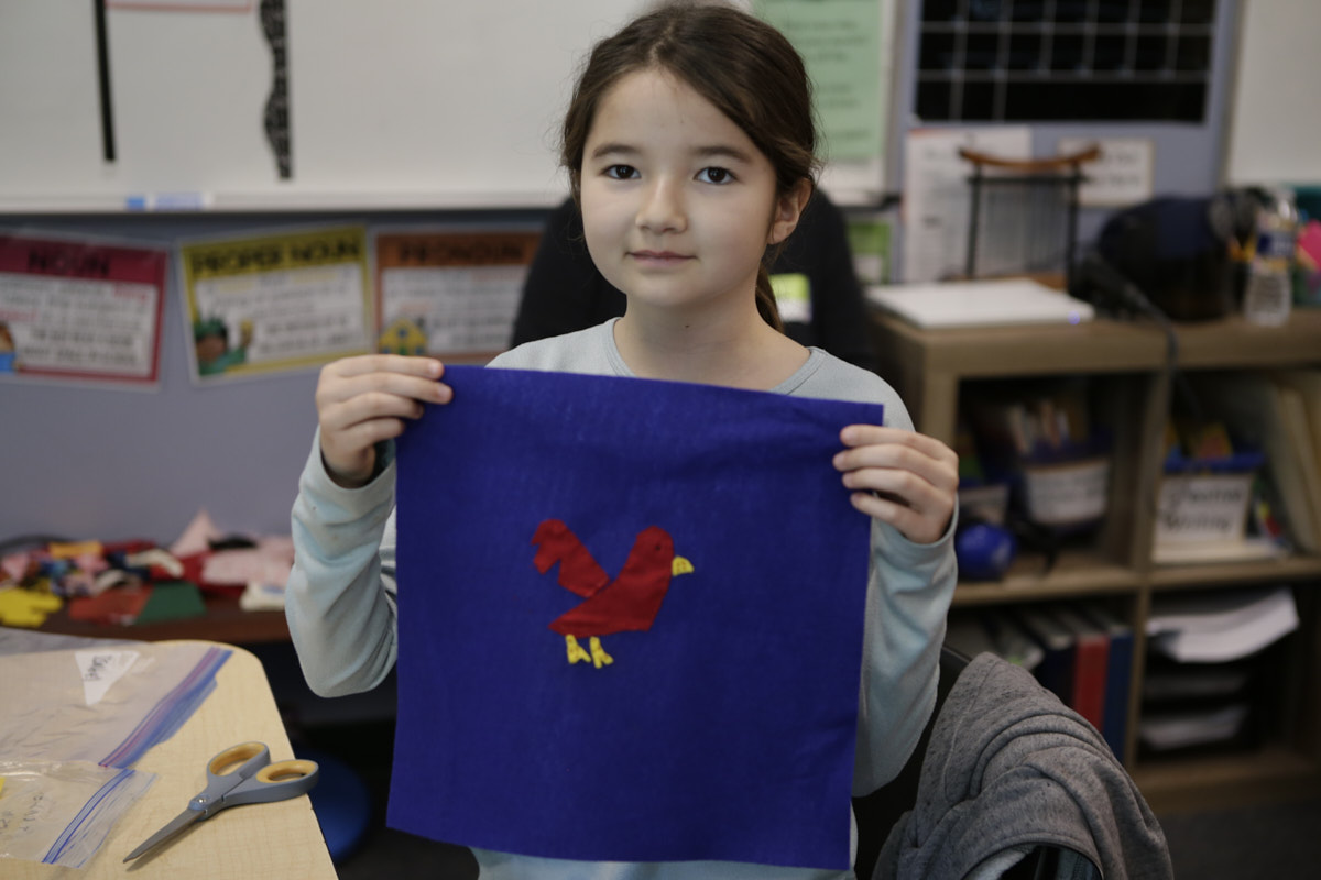 Photo of student holding fabric square featuring a cardinal