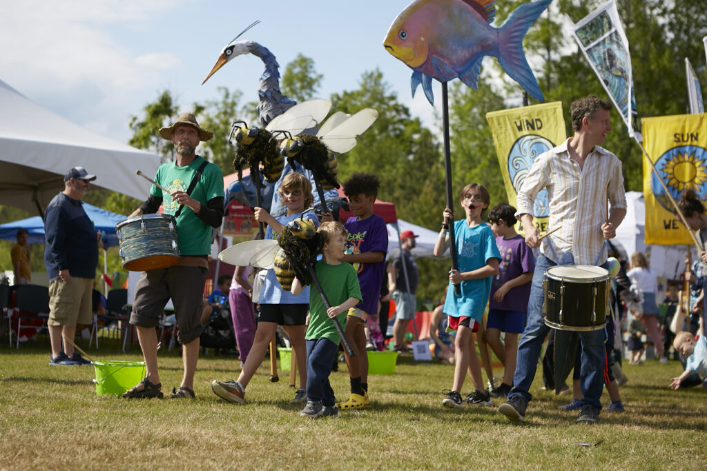 Members of Paperhand Puppet Intervention and festival attendees carry large puppets in the closing parade of ClydeFEST 2023