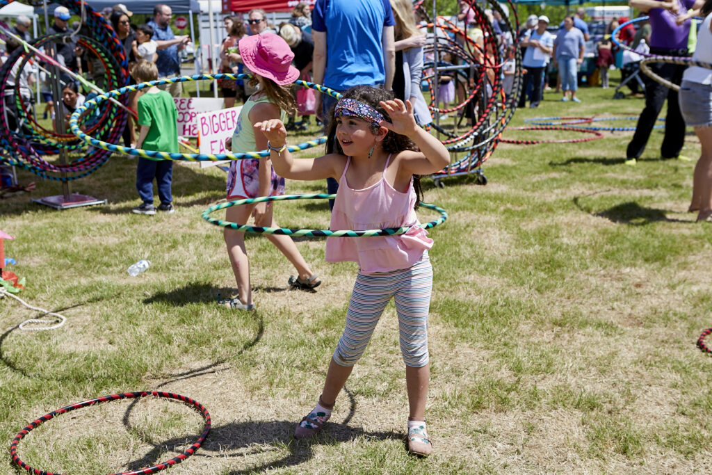 Photo of a girl in a pink shirt and long brown hair twirling a hula hoop around her waist