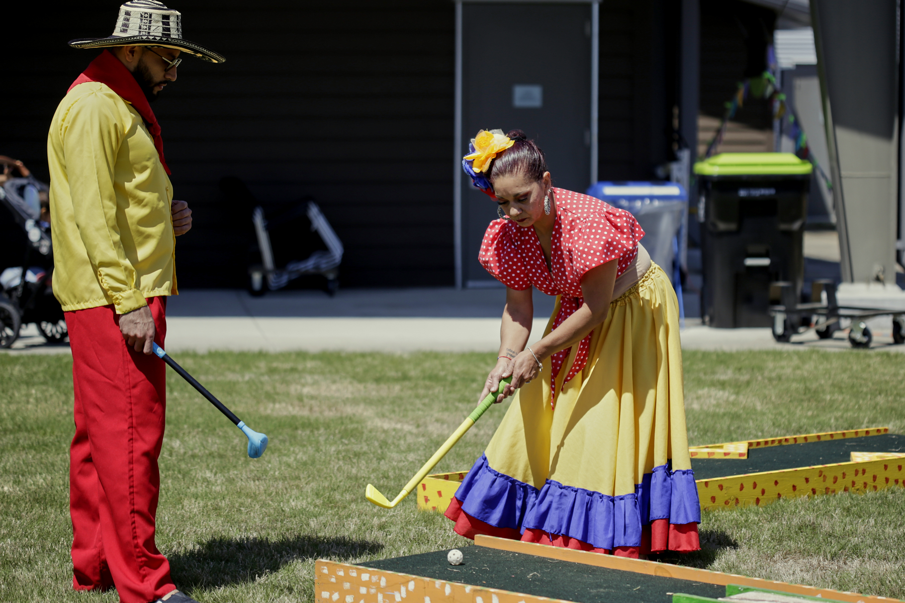 Members of Takiri Folclor Latino, in colorful traditional outfits, playing mini golf