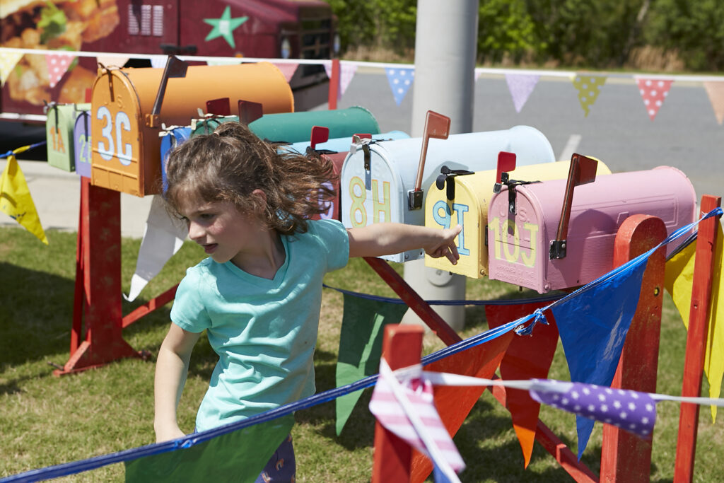 Photo of young girl playing an old fashioned carnival game with colorful mailboxes at ClydeFEST 2023
