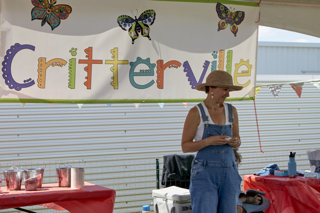 Photo of a woman standing in front of a sign that reads Critterville
