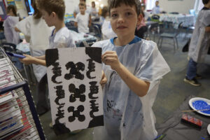 Fourth grade boy holds up his Adinkra block print