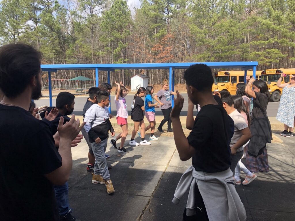 Photo of students, outside, raising their hands in a Flamenco exercise