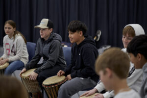 Photo of students holding drums and listening