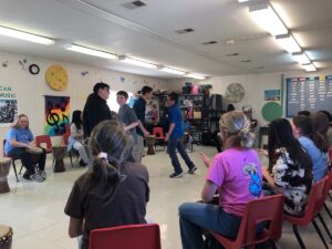 Two seventh grade students dance surrounded by other students playing drums