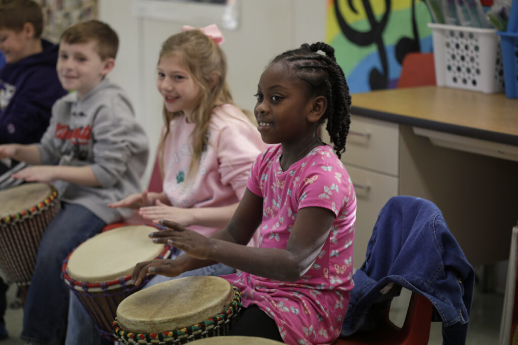 Photo of 2 small girls playing drum and smiling