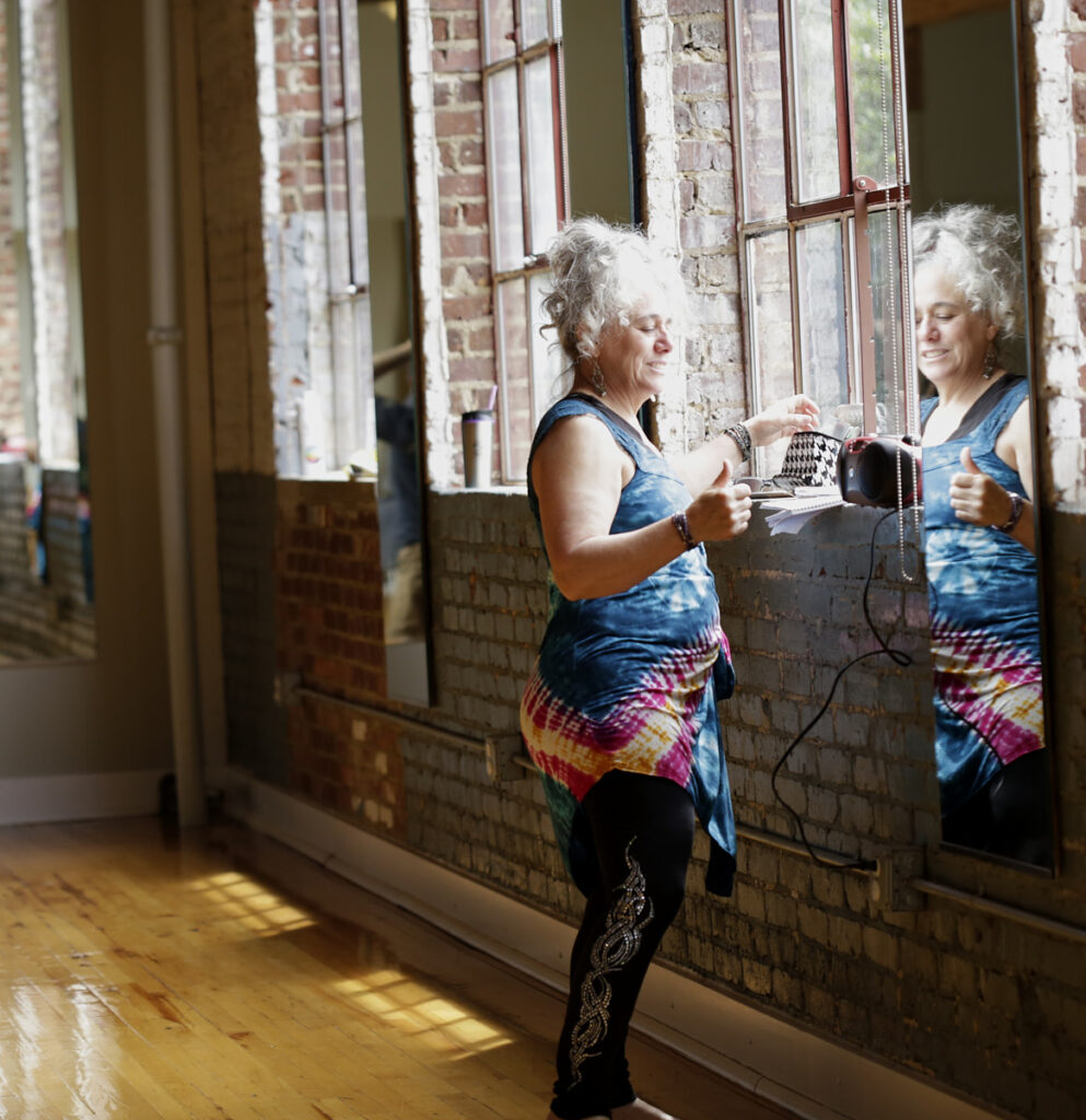 Photo of woman in tank top and yoga pants standing reflected in a mirror