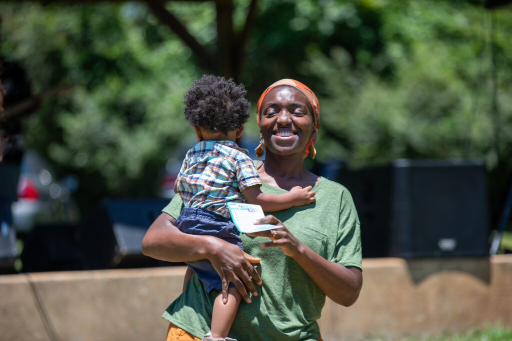 Photo of Black woman holding small child and smiling 
