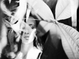 Layered black and white image of a woman's face with her eyes closed. Overlay of leaves and nature.