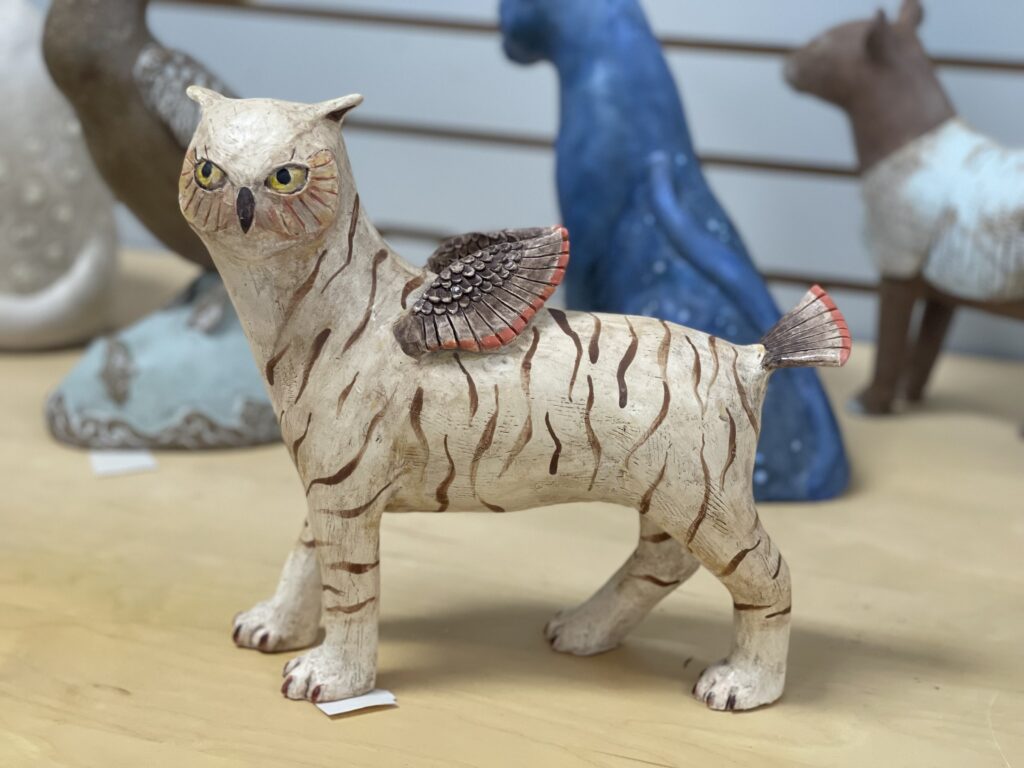 a sculpture of a creature with an owl's head and wings and a tiger body 