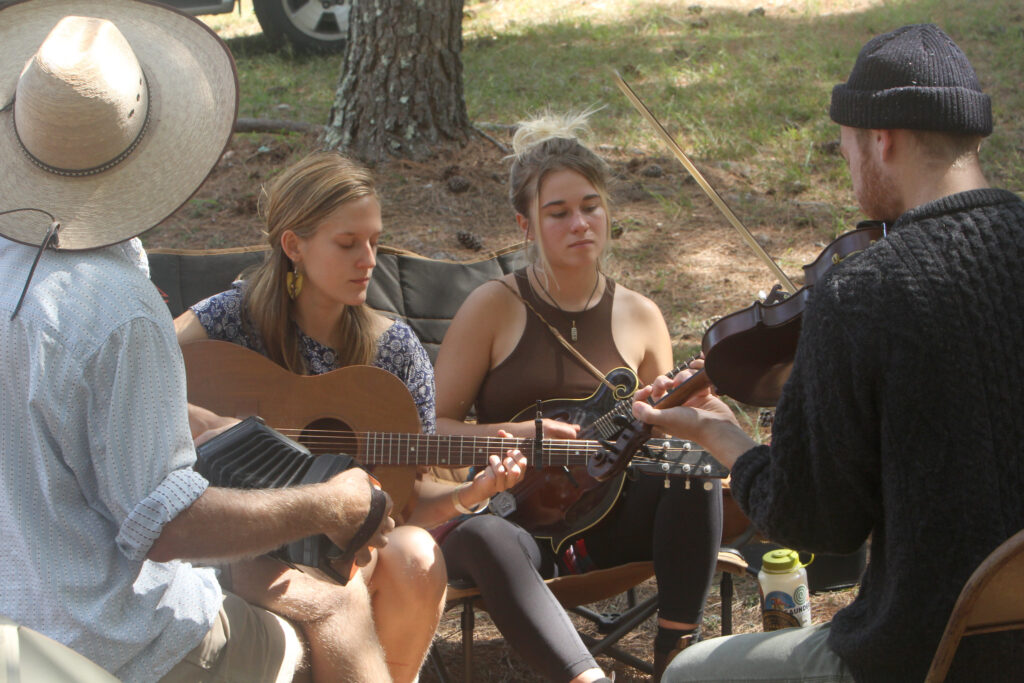 A group of young people, including two women, playing instruments outdoors