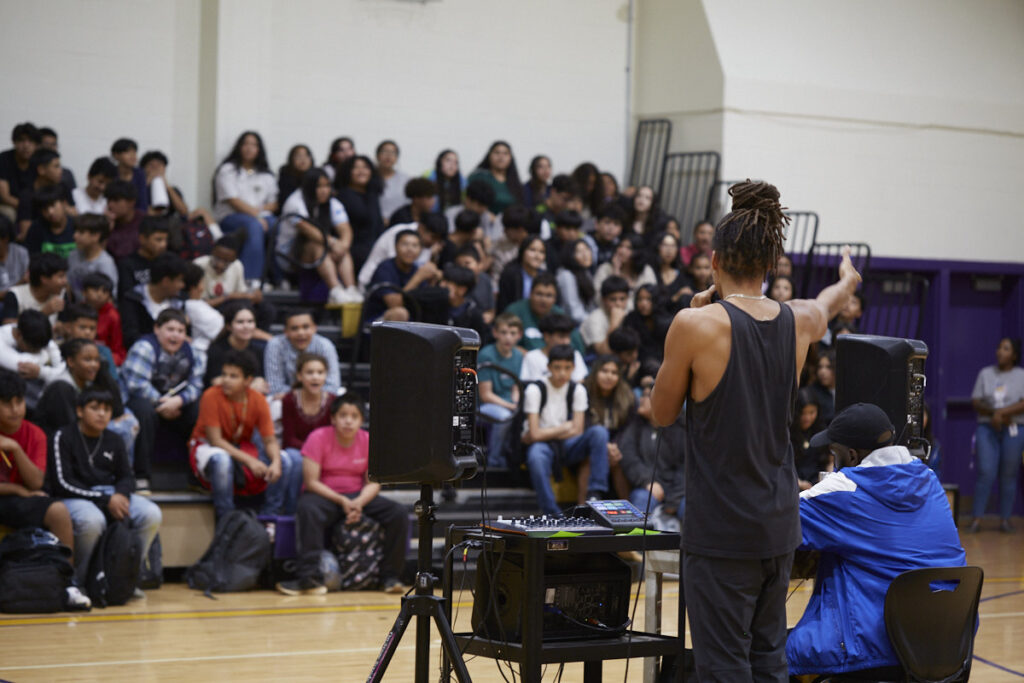 Pierce faces the student crowd, acting as a DJ for the student beat making battle and showcase