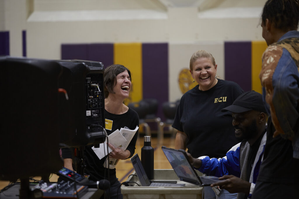 Cheryl and teachers laugh out loud during the beat making showcase in the school gym 