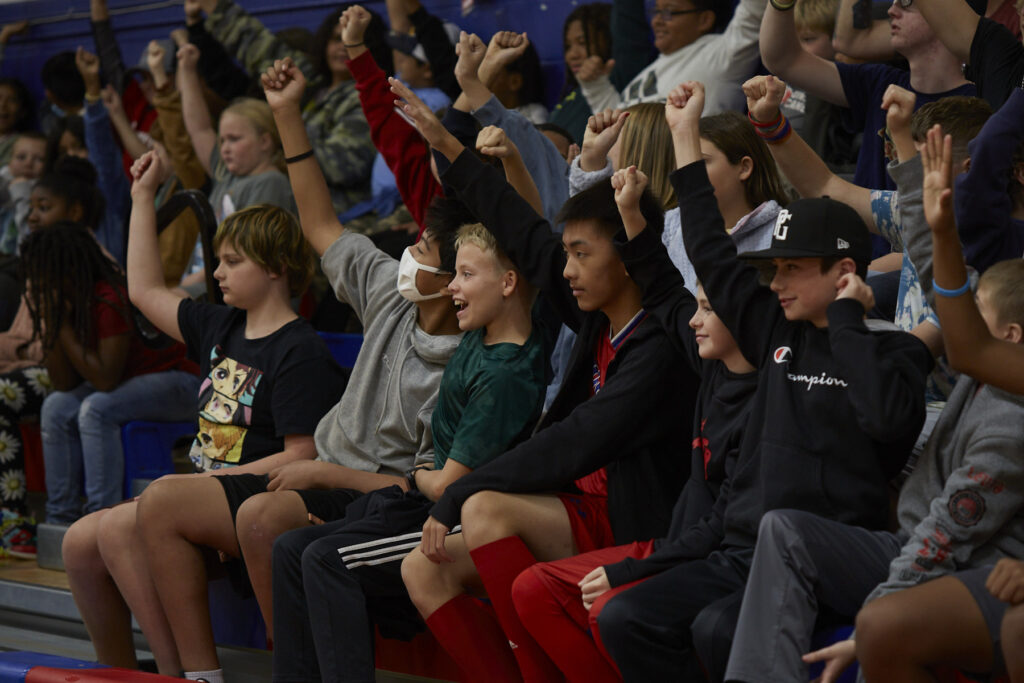 Flamenco dancers perform in a school gym in front of an audience of students.