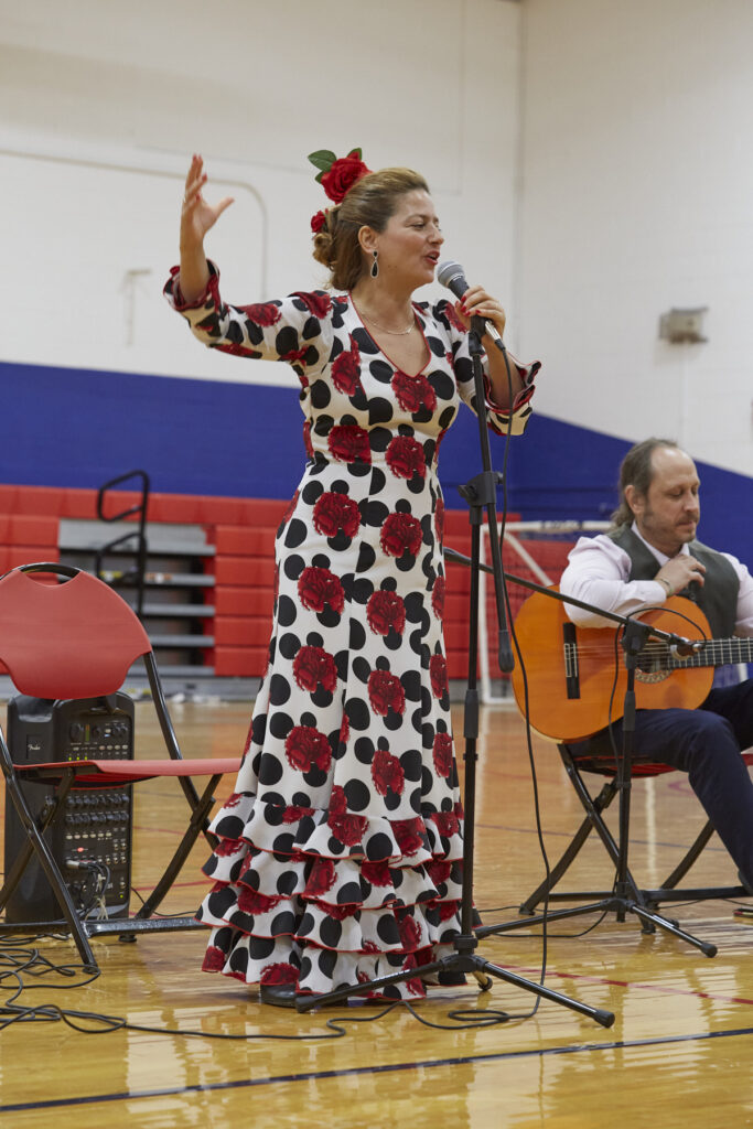 Flamenco dancers perform in a school gym in front of an audience of students.