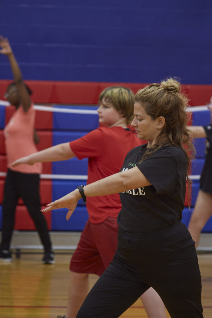 Flamenco dancers work with students to learn choreography in a school gym. 