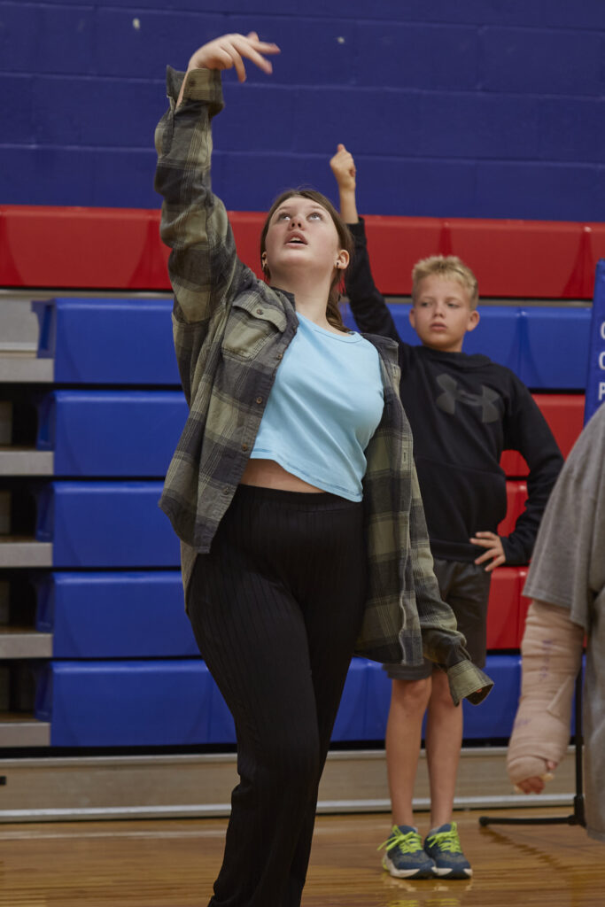 Flamenco dancers work with students to learn choreography in a school gym.