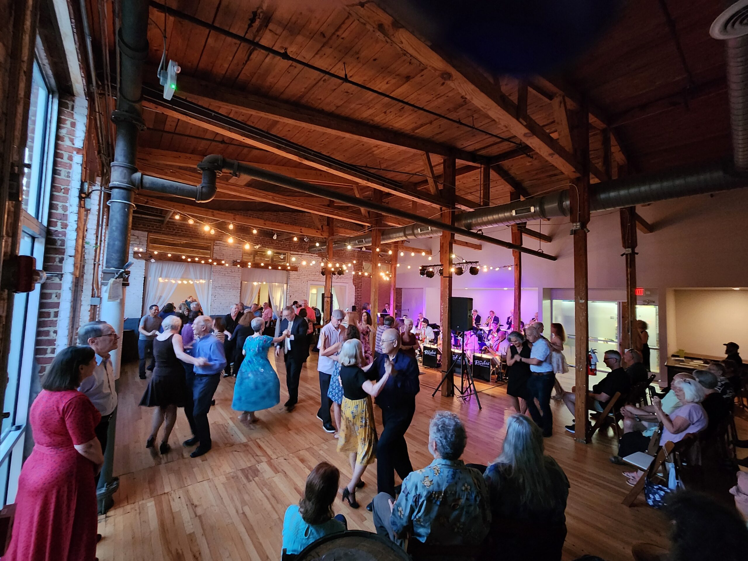 a large beamed hall filled with people dancing