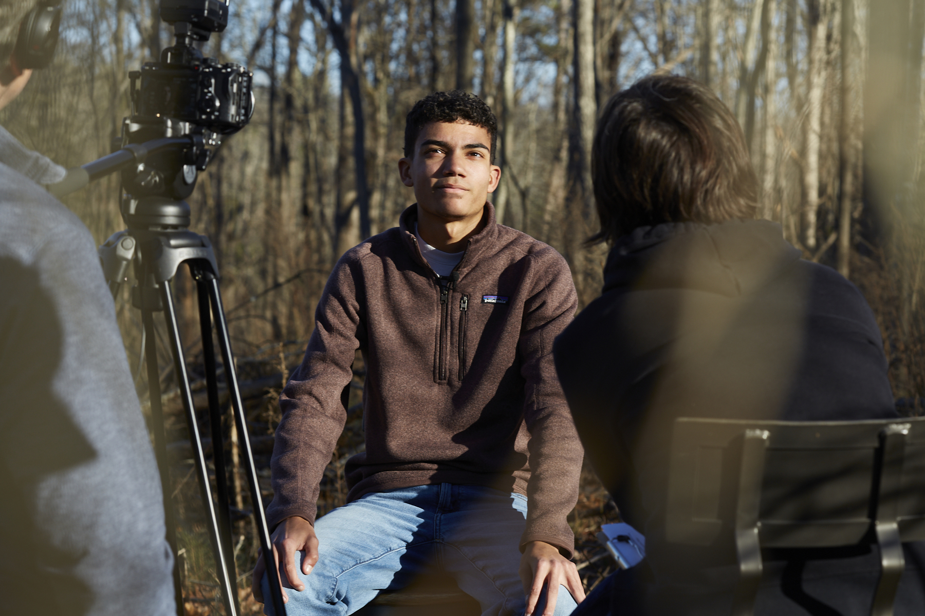 Photo of young black man sitting in a wooded setting
