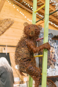 a sculpture of a bear on a ladder made of natural materials