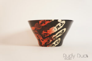 ceramic bowl painted with a neon handprint on black.