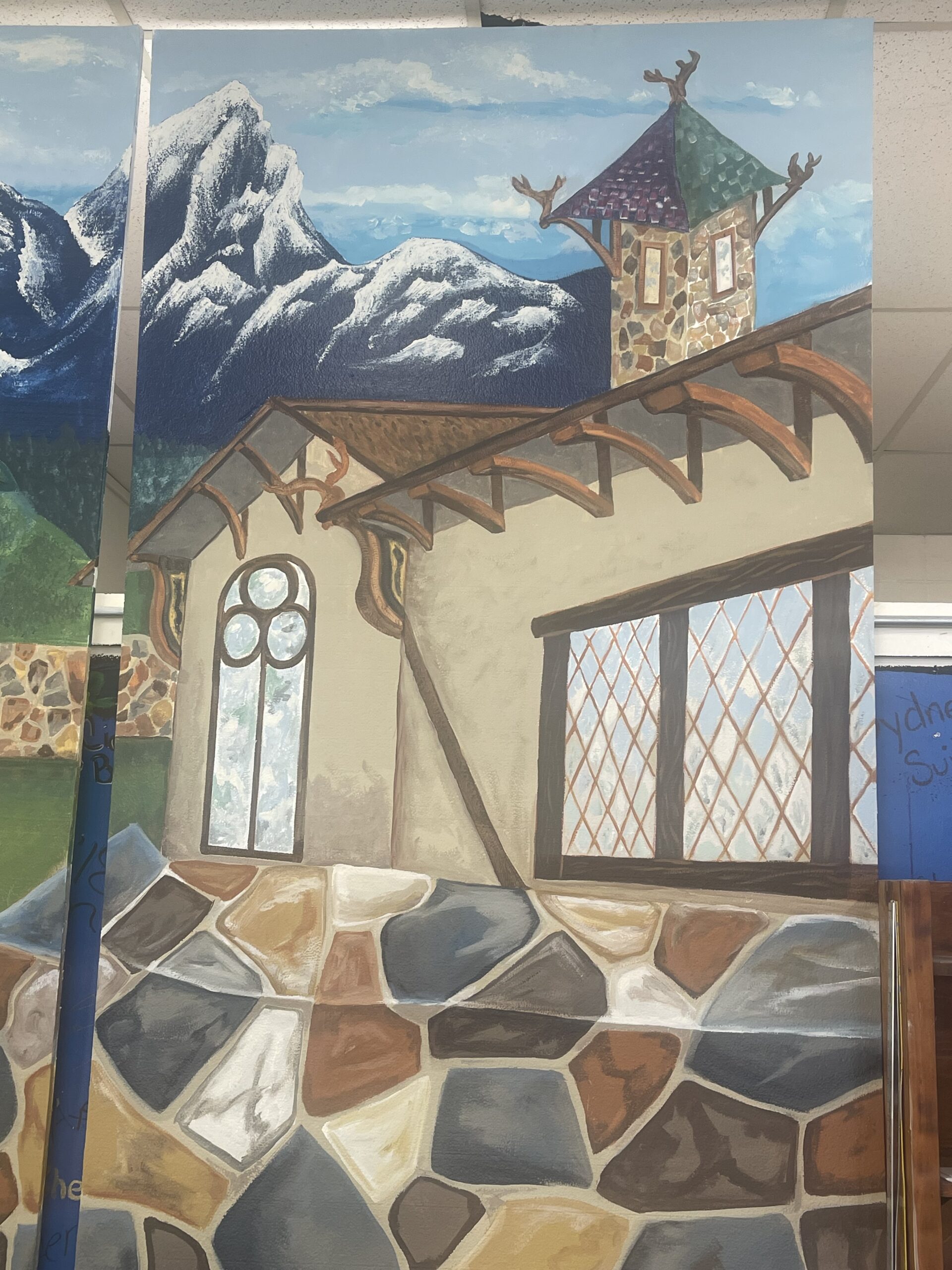 theatrical set backdrop painted with landscape of a nordic village and mountains.