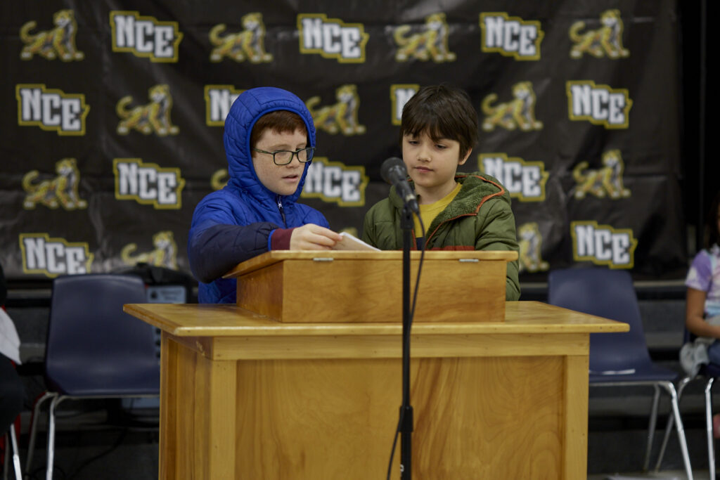 A student reads aloud at a podium. 