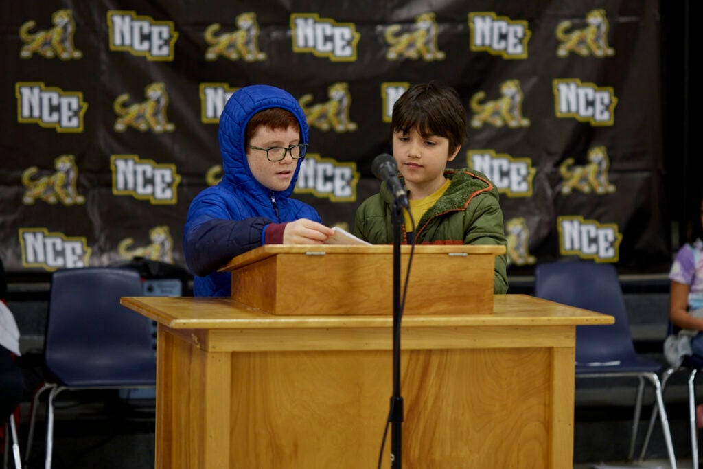 A student reads aloud at a podium.