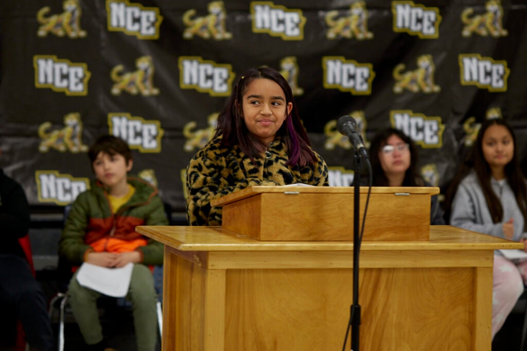 A student reads aloud at a podium.