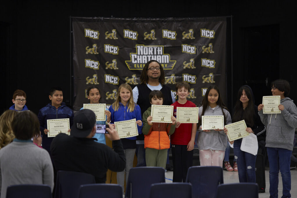Shabazz stands with a group of young poets holding certificates.