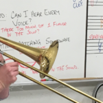 Man (Zach Wills) plays trombone in front of a whiteboard