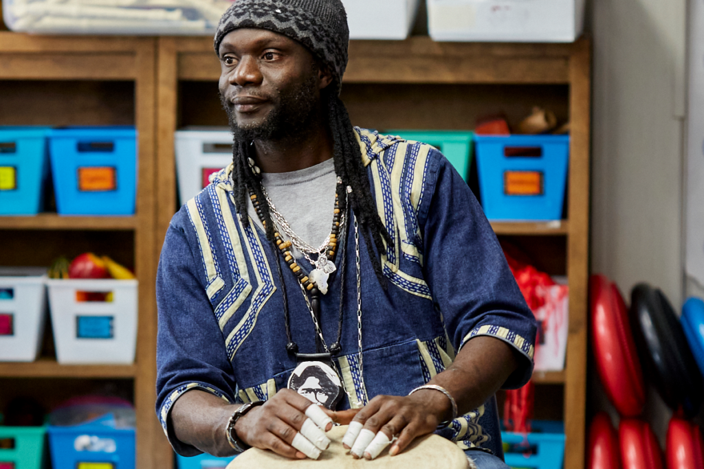 Photo of Black man wearing knit cap resting hands on drum