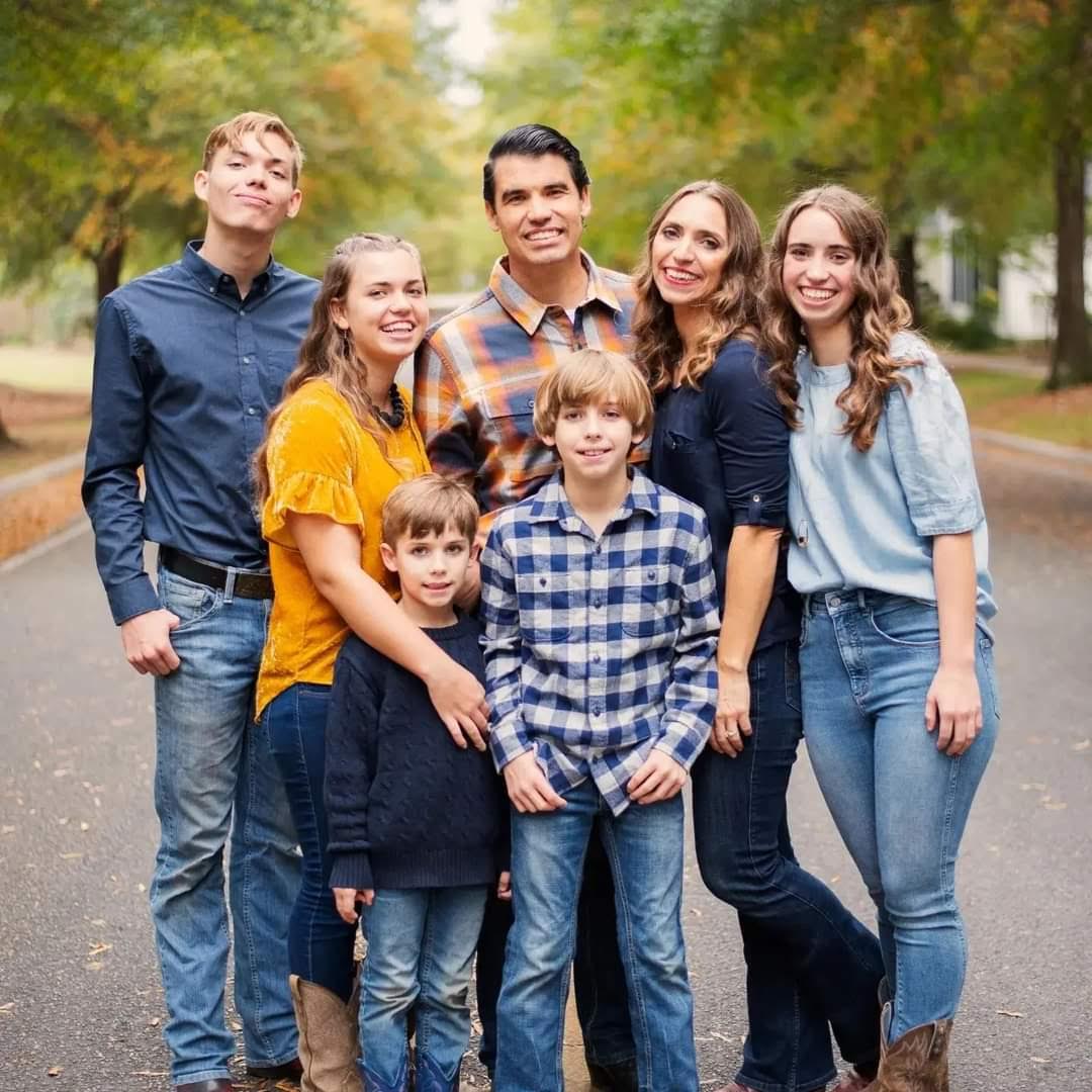 A family of 7 smiling for a portrait.