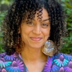 Smiling woman with light brown skin and curly brown hair.