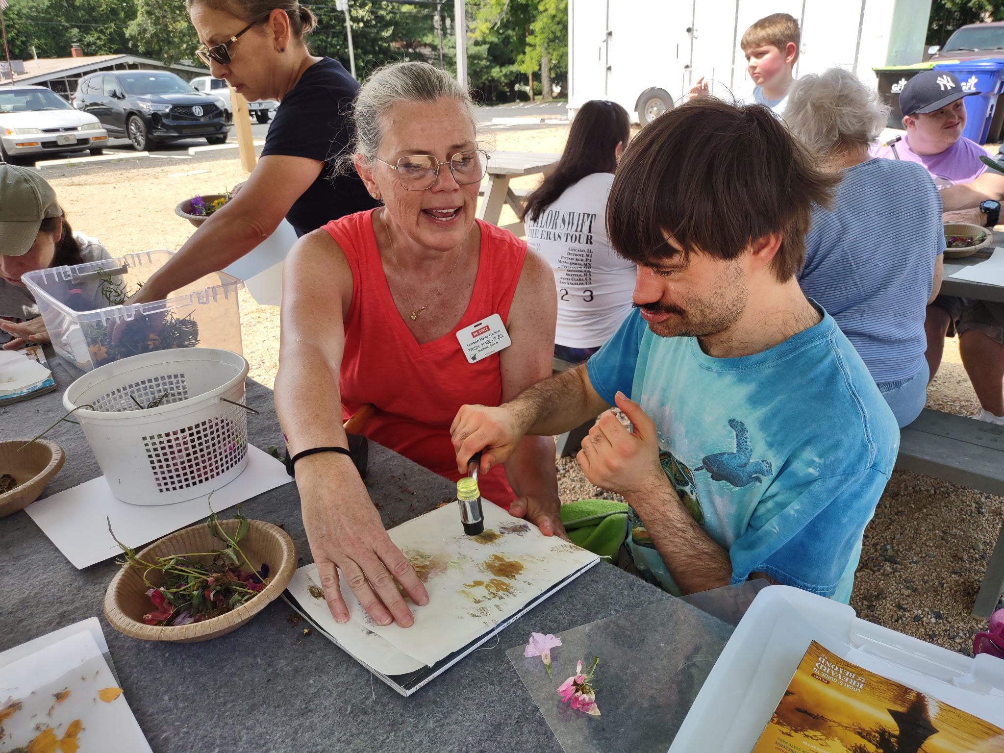 An older woman assists a younger man with an art project.