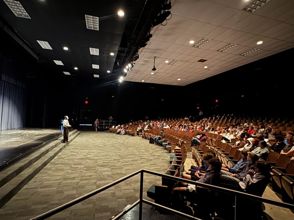 Actor standing in front of auditorium of students.