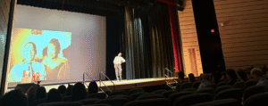 Actor on stage in front of projection of Emmett Till and his mother, Mayme Till.