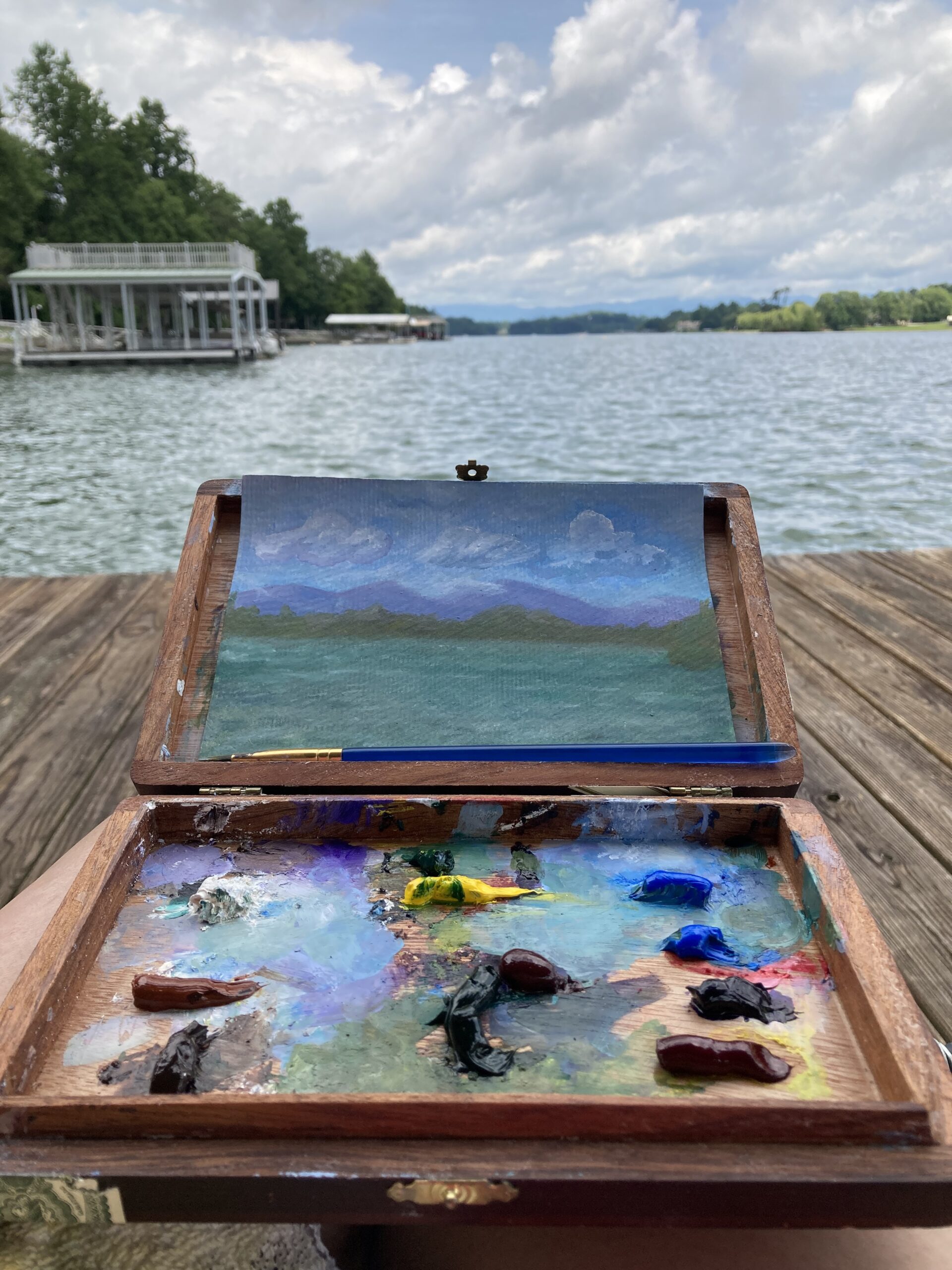 An artists travel paint box overlooking a lake scene.