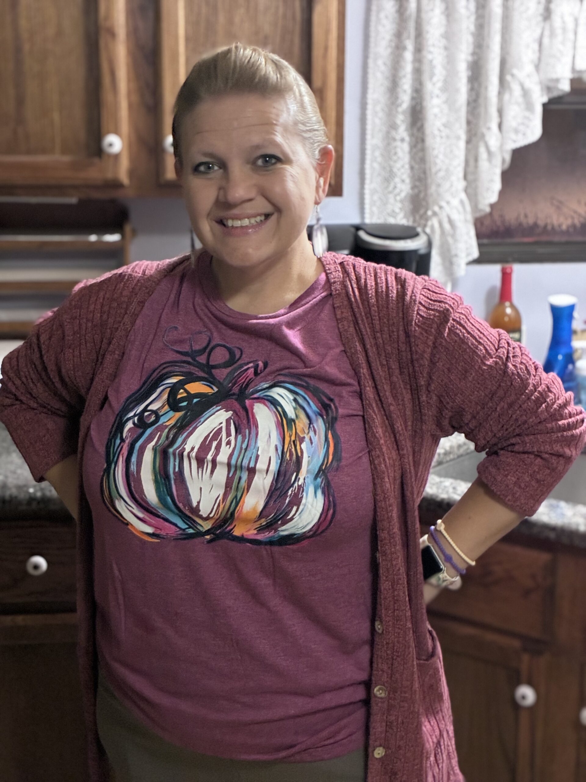 a woman with a slick back pony tail and burgundy pumpkin shirt.